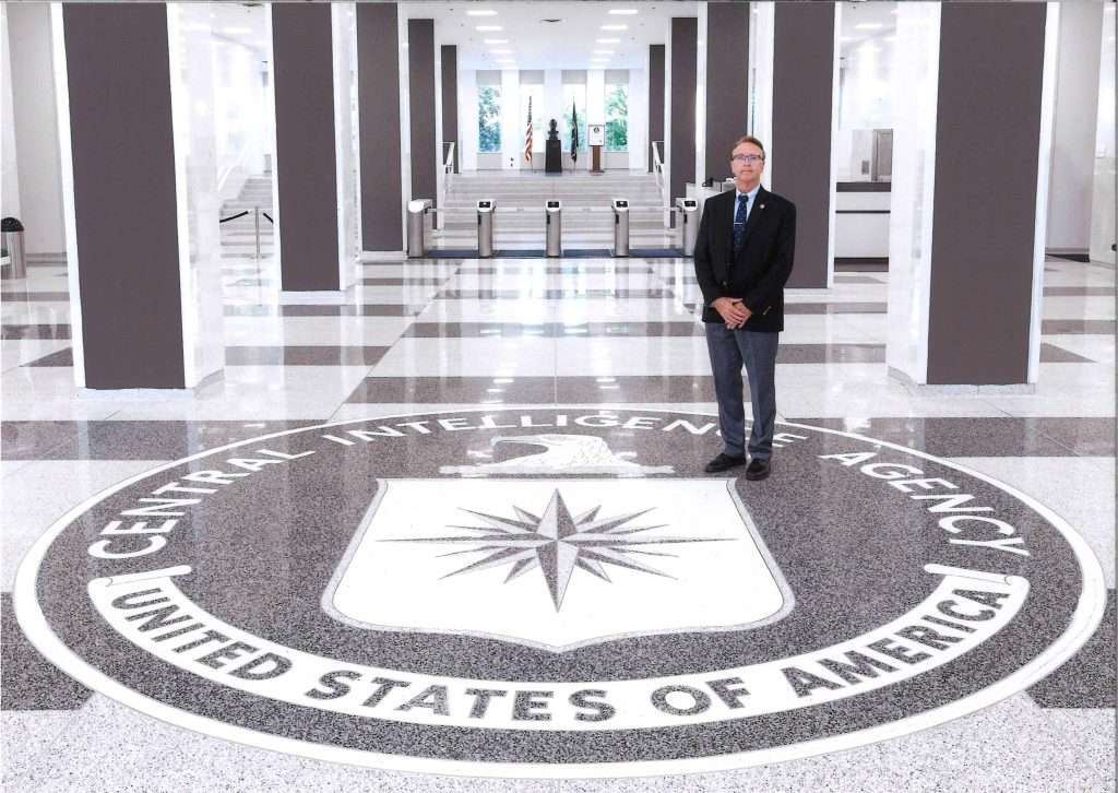 Steven L. Ririe standing on Central Intelligence Agency Seal